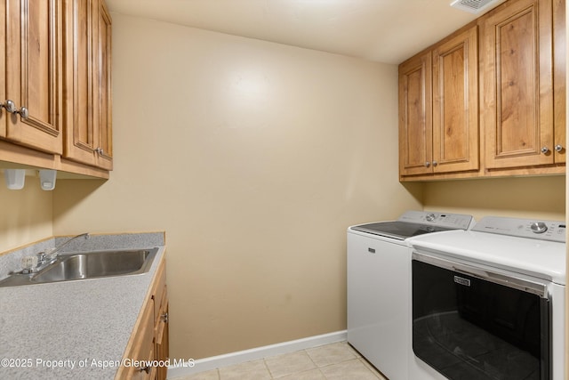 laundry room with light tile patterned floors, cabinets, washer and dryer, and sink