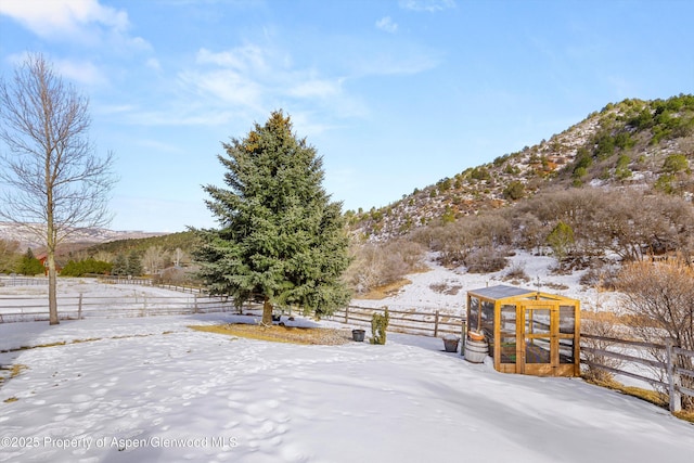 yard layered in snow with a rural view, a mountain view, and an outdoor structure