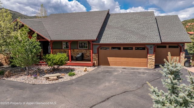 10 Laird Ln, Glenwood Springs, CO 81601 - view of front of house featuring stone siding, an attached garage, driveway, a shingled roof, and a porch