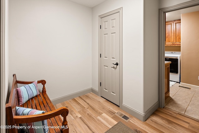 sitting room with washer / dryer and light hardwood / wood-style flooring