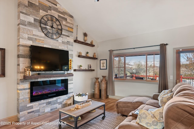 living room featuring vaulted ceiling, hardwood / wood-style flooring, and a stone fireplace