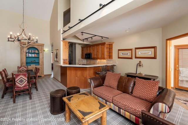 living room with a notable chandelier, lofted ceiling, and track lighting