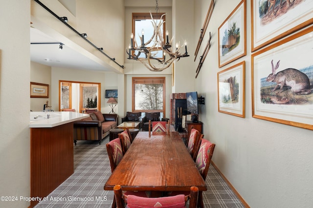 carpeted dining area featuring a high ceiling and an inviting chandelier