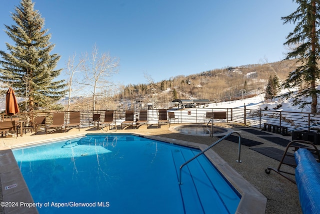 snow covered pool featuring a mountain view and a patio area