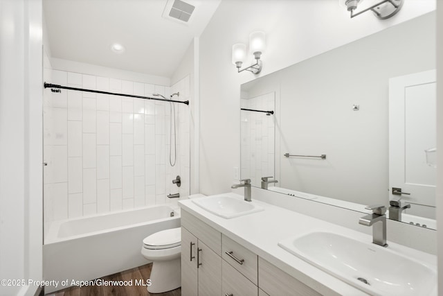 full bathroom featuring hardwood / wood-style flooring, tiled shower / bath, vanity, and toilet