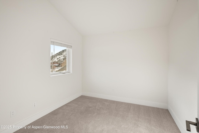 carpeted spare room with vaulted ceiling