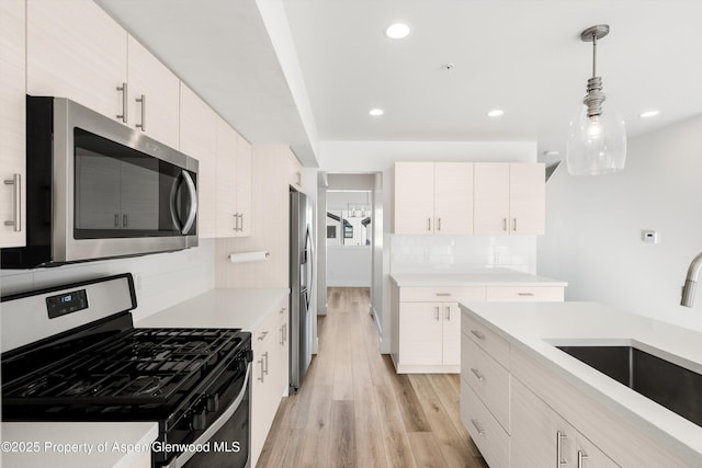 kitchen with sink, backsplash, stainless steel appliances, decorative light fixtures, and light wood-type flooring