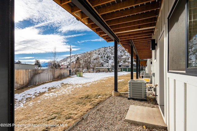 yard layered in snow featuring central AC unit and a mountain view