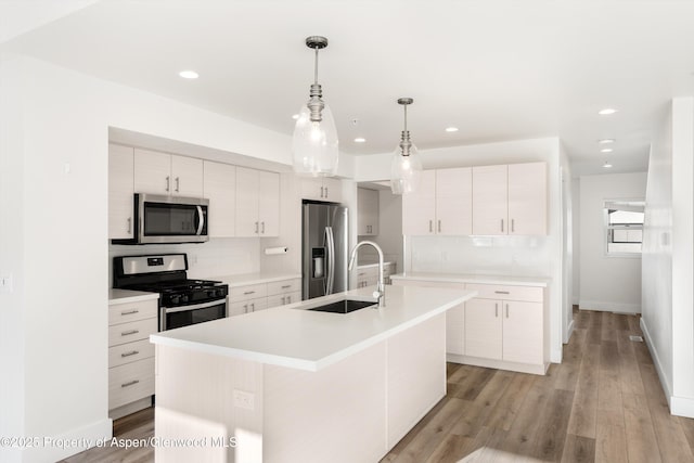 kitchen featuring sink, white cabinetry, a kitchen island with sink, stainless steel appliances, and tasteful backsplash