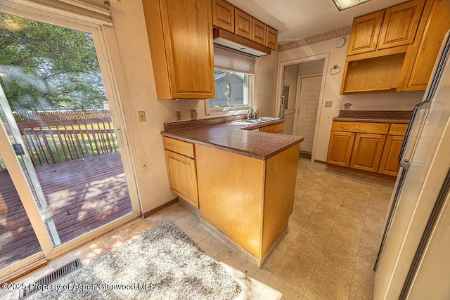 kitchen featuring plenty of natural light, sink, refrigerator, and kitchen peninsula