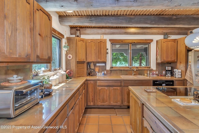 kitchen with tile counters, sink, wooden ceiling, beamed ceiling, and light tile patterned floors