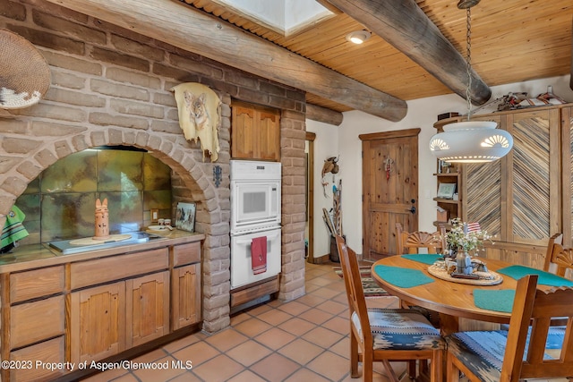 kitchen with beam ceiling, a skylight, white double oven, pendant lighting, and wood ceiling