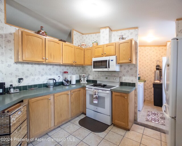 kitchen with light tile patterned flooring, white appliances, and washing machine and clothes dryer