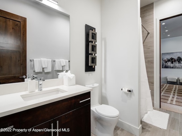 bathroom featuring toilet, a shower with shower curtain, and vanity