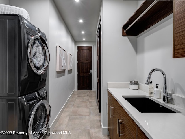 clothes washing area featuring stacked washer and clothes dryer and sink