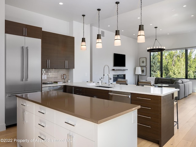 kitchen with a center island with sink, appliances with stainless steel finishes, white cabinets, backsplash, and sink