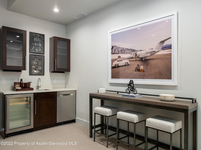 bar featuring dishwasher, beverage cooler, dark brown cabinets, light carpet, and sink