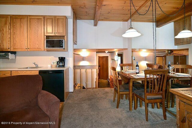 carpeted dining space featuring beam ceiling, ceiling fan, sink, and wood ceiling