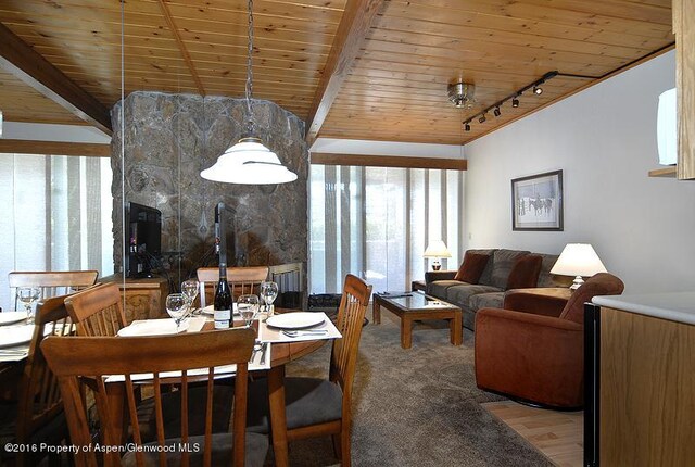 dining area featuring a wood stove, wooden ceiling, track lighting, and hardwood / wood-style flooring