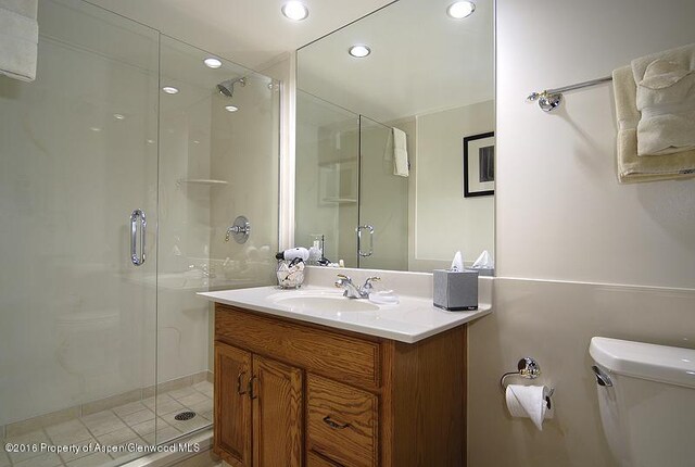 bathroom featuring a shower with door, vanity, and toilet