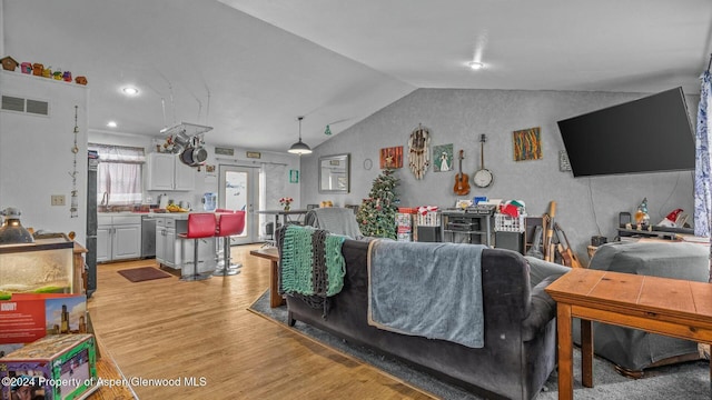 living room with french doors, light wood-type flooring, and vaulted ceiling