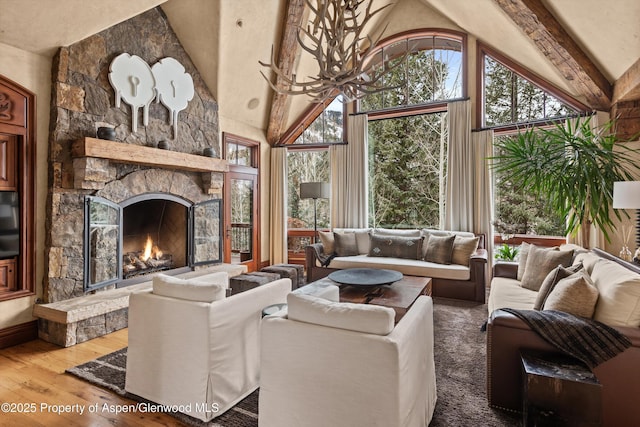 living area featuring high vaulted ceiling, a fireplace, hardwood / wood-style floors, and an inviting chandelier