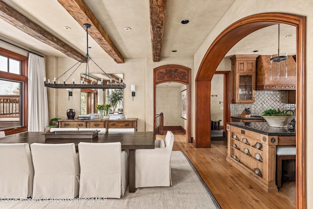 interior space with light wood finished floors, a notable chandelier, arched walkways, and a wealth of natural light