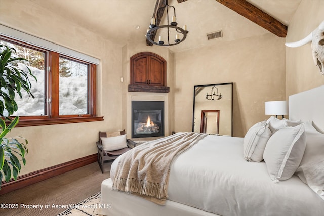 bedroom featuring vaulted ceiling with beams, visible vents, an inviting chandelier, a glass covered fireplace, and baseboards