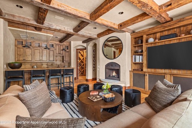 living area featuring visible vents, beam ceiling, coffered ceiling, and a lit fireplace