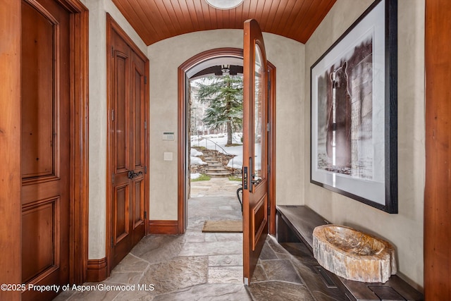 entrance foyer featuring lofted ceiling, baseboards, and stone tile floors