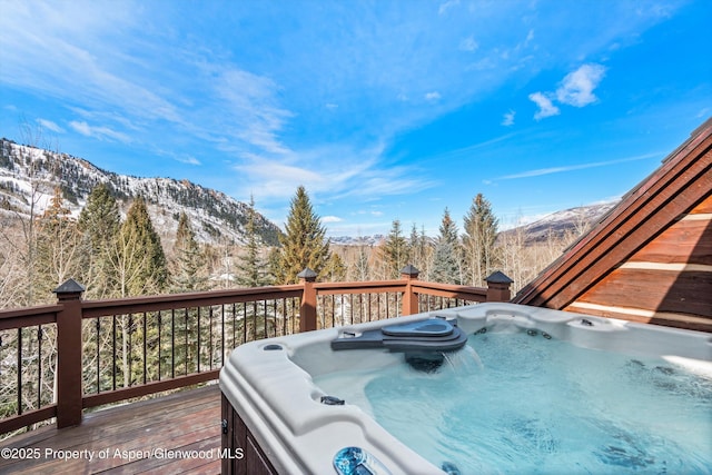 deck with an outdoor hot tub and a mountain view