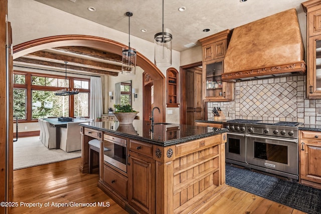 kitchen with hardwood / wood-style flooring, double oven range, custom range hood, and built in microwave