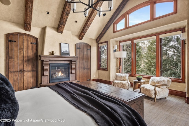 bedroom featuring high vaulted ceiling, beamed ceiling, a glass covered fireplace, and baseboards