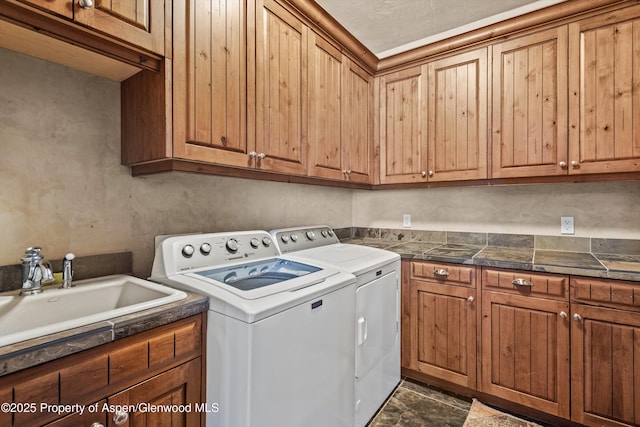 laundry area featuring washing machine and dryer, cabinet space, and a sink