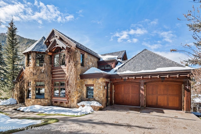 view of front of house with a garage, stone siding, and driveway