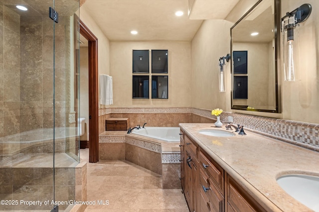 full bath featuring a garden tub, double vanity, recessed lighting, a sink, and a shower stall