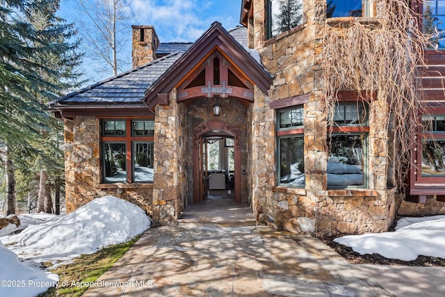 doorway to property featuring stone siding and a chimney