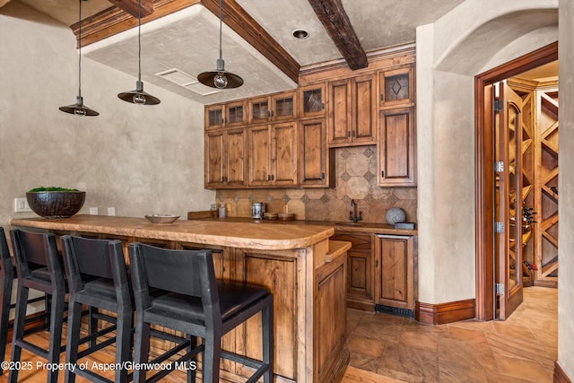 bar with arched walkways, backsplash, beam ceiling, wet bar, and stone finish flooring