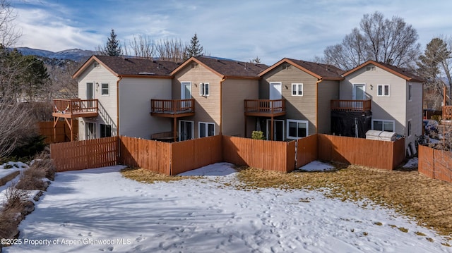 snow covered back of property featuring a balcony