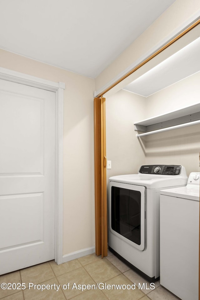 clothes washing area with independent washer and dryer and light tile patterned floors