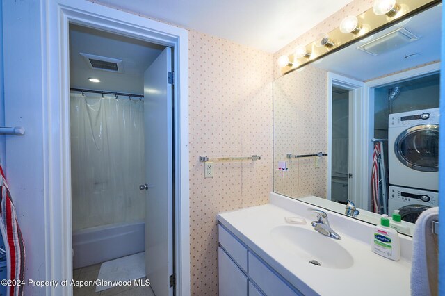 bathroom featuring tile patterned flooring, vanity, stacked washing maching and dryer, and walk in shower