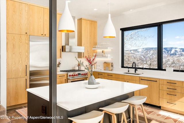 kitchen with sink, hanging light fixtures, a breakfast bar, a kitchen island, and high end appliances