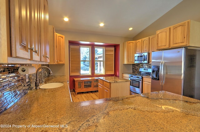 kitchen featuring lofted ceiling, sink, tasteful backsplash, a kitchen island, and stainless steel appliances