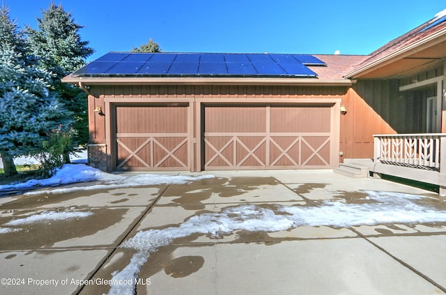 snow covered garage with solar panels