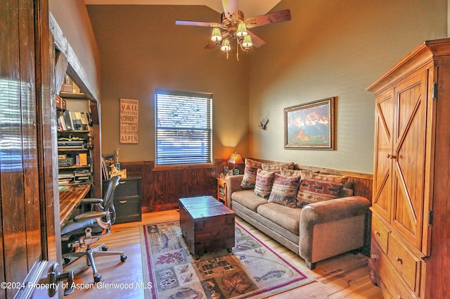 home office featuring light wood-type flooring, wooden walls, ceiling fan, and lofted ceiling