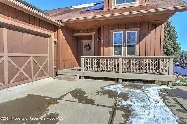 property entrance featuring covered porch and a garage