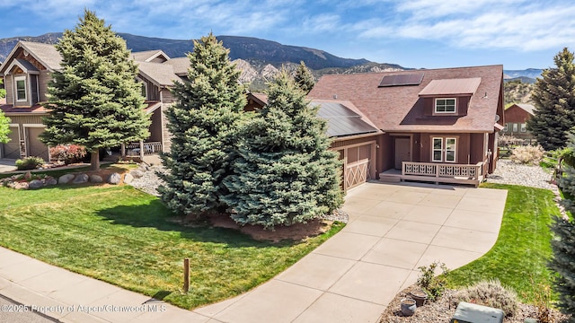 168 Blackhawk Dr, New Castle, CO 81647 - view of front facade featuring roof mounted solar panels, a mountain view, concrete driveway, and a front lawn