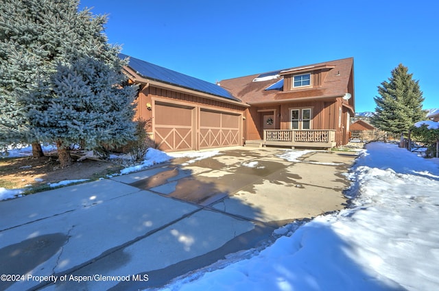 view of front facade with covered porch, a garage, and solar panels