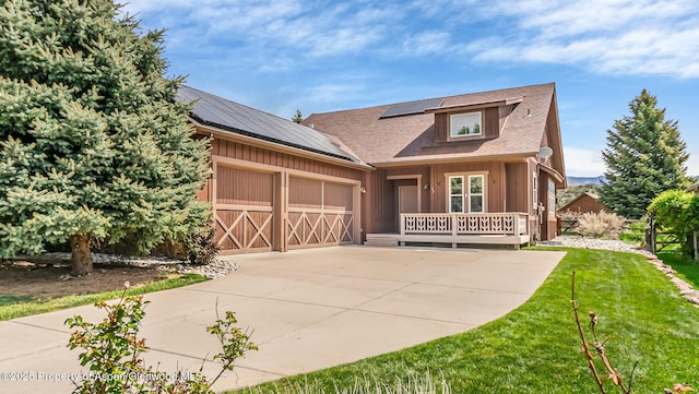 168 Blackhawk Dr, New Castle, CO 81647 - view of front of property with an attached garage, solar panels, a front lawn, concrete driveway, and a porch