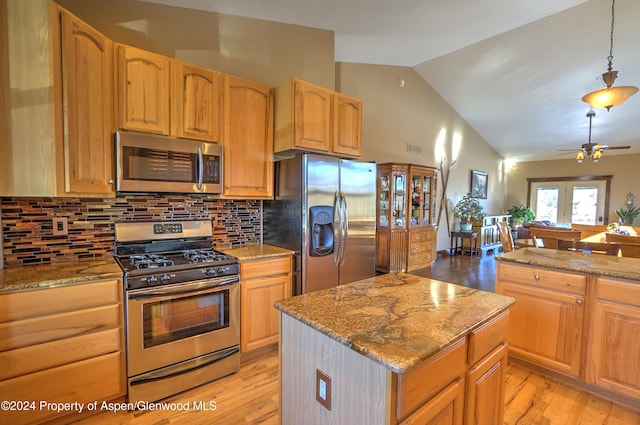 kitchen with a center island, ceiling fan, appliances with stainless steel finishes, decorative light fixtures, and light stone counters